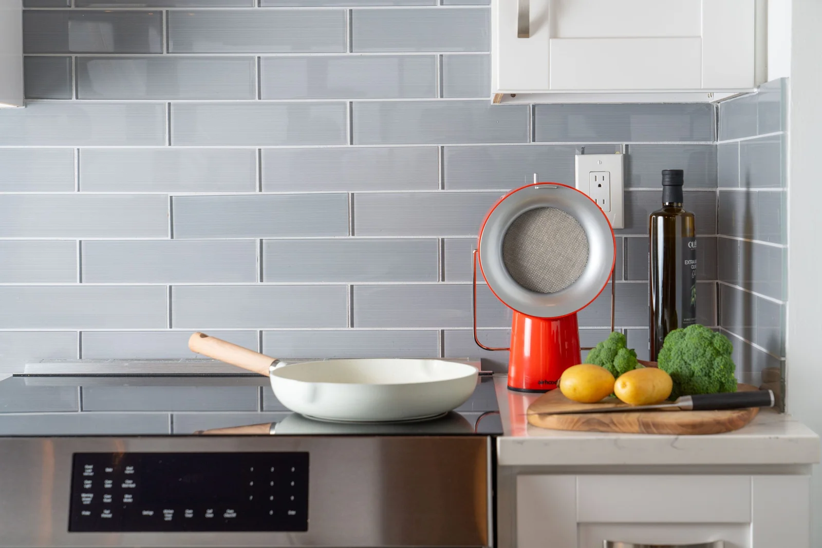 Red AirHood portable kitchen air cleaner beside a pan in a home kitchen